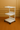 White rolling cart with three shelves on a brown floor and wall.